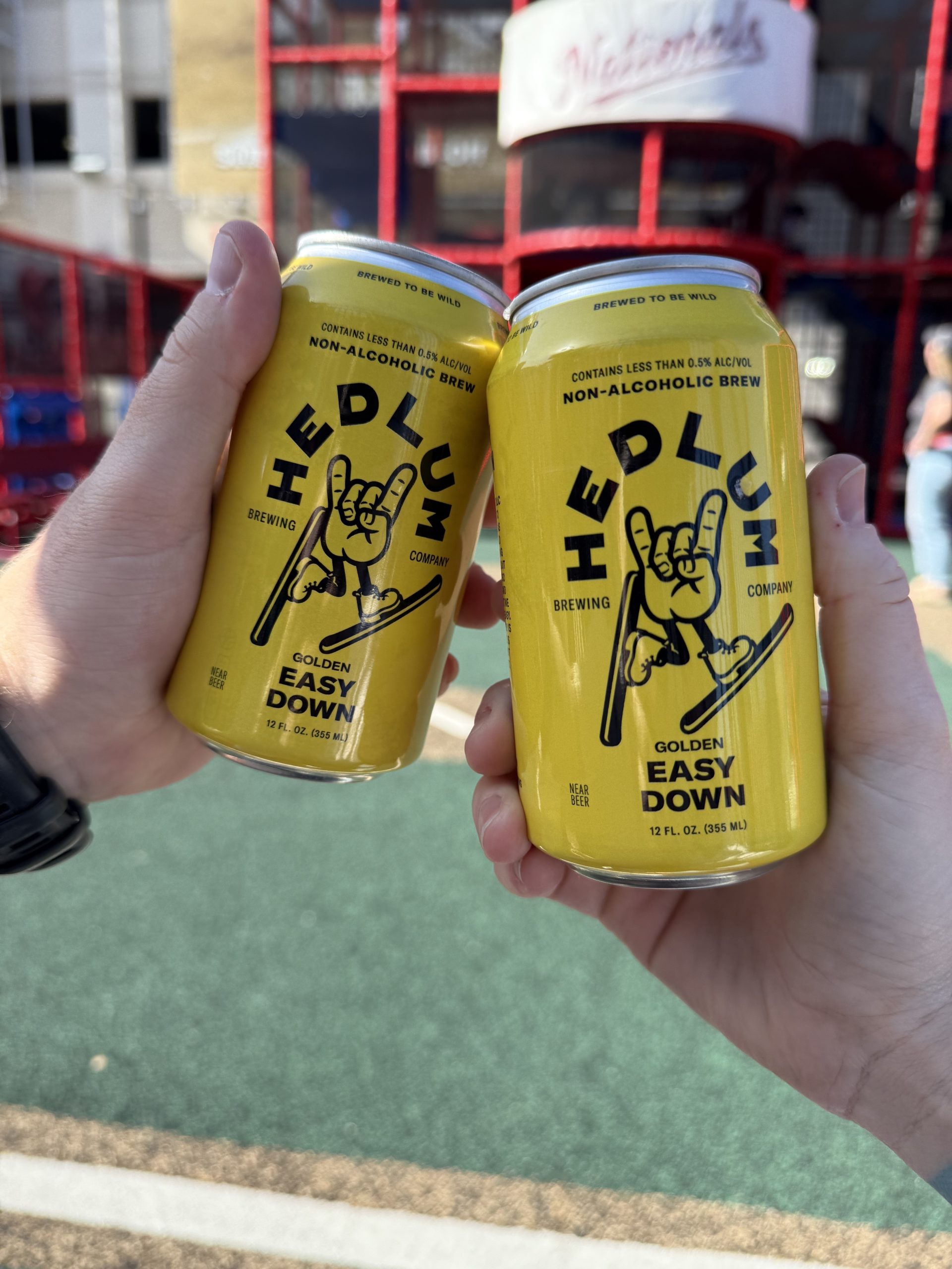 Two hands making a cheers with two cans of Hedlum Non Alcoholic Golden Beer